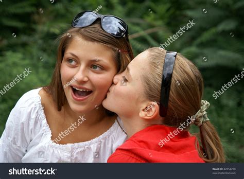 Two Beautiful Cheerful Teenage Girls Kissing Outdoors Stock Photo