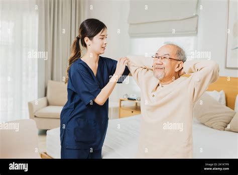 Asian Nurse Woman Assisting Old Man Warming Up Exercises For The Upper