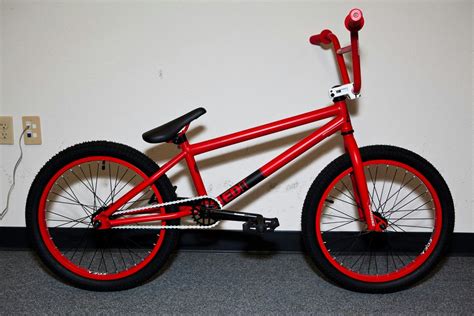 A Red Bike With Black Spokes Is Parked In A Room Next To A Wall