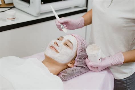 Professional Esthetician Apply Face Mask To The Client`s Face In Spa Beauty Center Young Woman