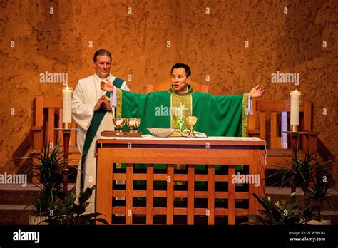 A Robed Deacon And An Asian American Priest Celebrate Mass At The Altar