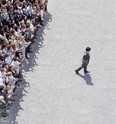 Businessman Walking Away From Clapping Crowd Stock Photo Download