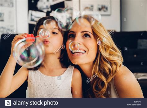 Feliz Madre Con Su Hija En Casa Soplando Burbujas De Jabón Fotografía