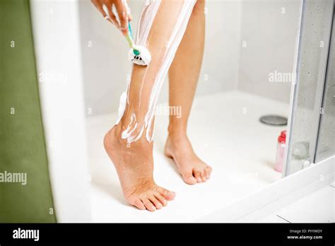 Woman Shaving Her Legs With Razor And Foam In The Shower Cabin Stock