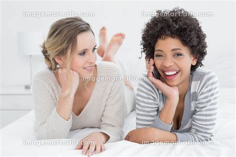 Young Woman Looking At Cheerful Friend On Call While Lying In Bed At Homeの写真素材 31763642 イメージマート