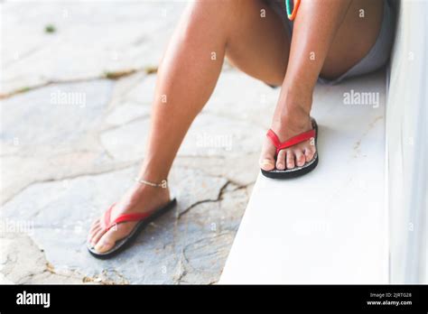 Low Section Of Womans Legs Sitting Outdoors Wearing Shorts And Flip