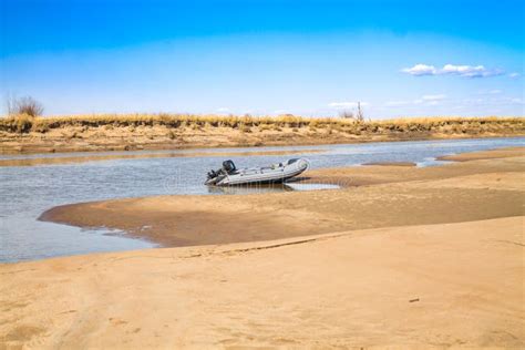 River Motor Boat Near Sandy River Bank With Golden Dunes And Blue Water