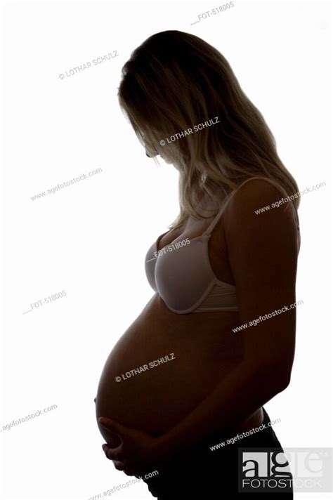 Silhouette Of A Pregnant Woman Touching Her Abdomen Stock Photo