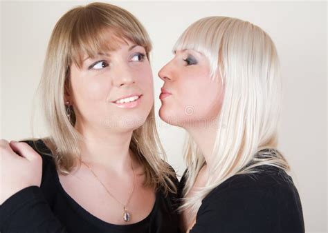 Brunett And Blond Girl Kissing In The Cheeck Royalty Free Stock Images