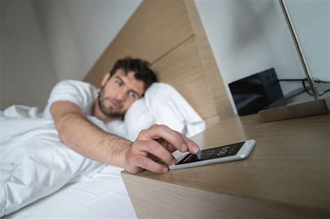 Man Waking Up In The Morning And Snoozing The Alarm Stock Photo