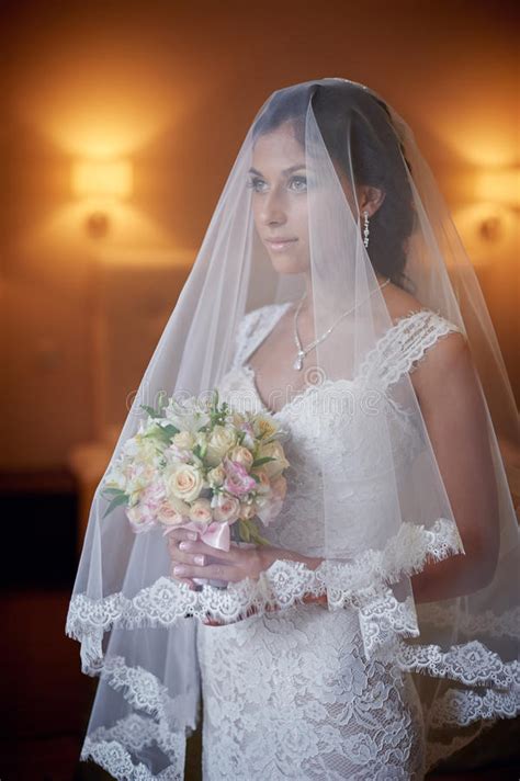 Portrait Of Beautiful Bride In A Wedding Veil Holding Bouquet Stock