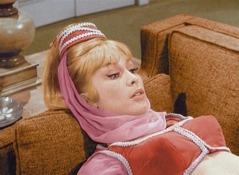 A Woman Sitting On Top Of A Brown Couch Wearing A Pink Dress And Head Scarf