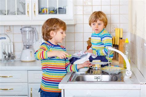 Two Little Kid Boys Washing Dishes In Domestic Kitchen Stock Photo By