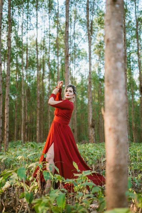 Woman In Red Long Sleeves Dress Standing In The Forest Surrounded By