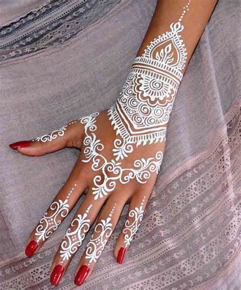 a woman s hand with white henna on it
