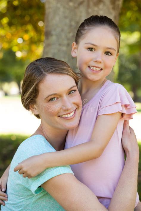 Madre Sonriente Que Abraza A Su Hija En El Parque Imagen De Archivo