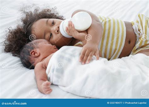 Little African Older Sister Sucking Milk From Bottle Hugging And Take Good Care Of Her Newborn