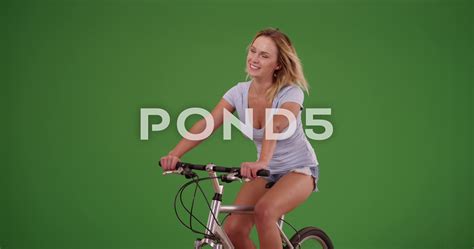 White Woman Riding Her Bike To Camera Left On Green Screen Stock
