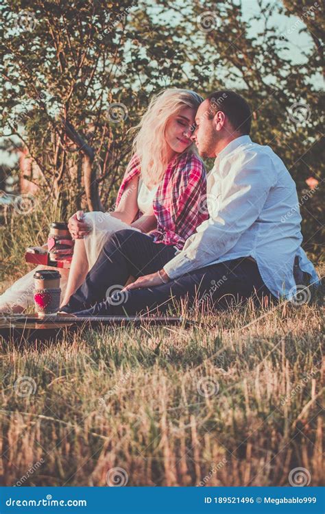 Romantic Couple Hugging While Having Picnic In Sunset Light Stock Photo
