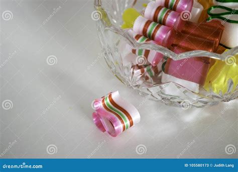 One Broken Piece Of Ribbon Candy Beside Filled Bowl Stock Image