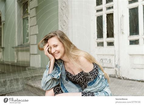 Porträt Einer Lachenden Blonden Frau In Kleid Und Jeansjacke Die Im Freien Sitzt Ein