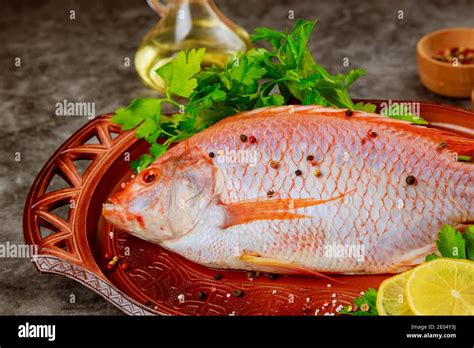 Pink Tilapia Fish With Herbs And Lemon On Tray Close Up Stock Photo