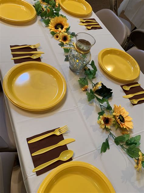 the table is set with yellow plates and sunflowers on each plate along with place settings