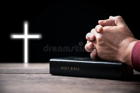 Hands Folded In Prayer On Holy Bible With Cross In Church Concept For
