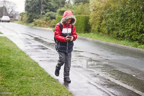 Stock Photo Child Walking To School In The Rain Using A Smart Phone