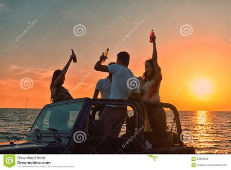 Five Young People Having Fun In Convertible Car At The Beach At Sunset