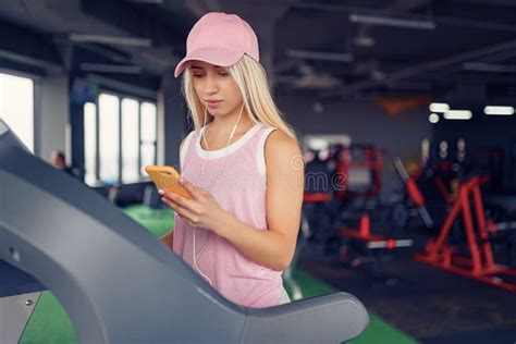 Side View Of Sporty Blonde Woman Exercising On Treadmill In Gym Stock