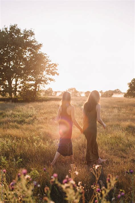 Two Unrecognizable Girlfriends Walking By Summer Field By Stocksy Contributor Liliya