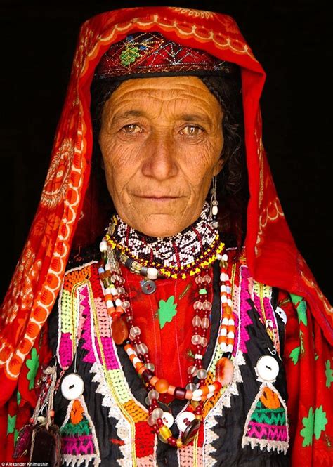 a picture of a wakhi woman pictured dressed in a brightly coloured red garment marked with a