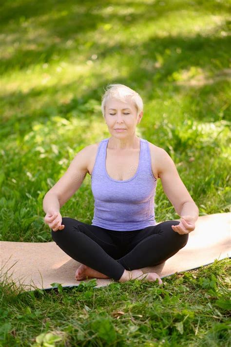 Athletic Middle Aged Woman Doing Yoga Outdoors In A City Park