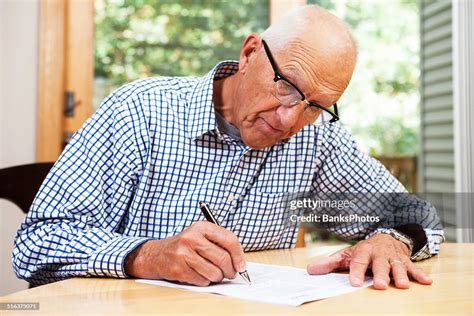 Senior Man Filling Out Paperwork Signing Document High Res Stock Photo