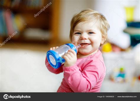Cute Adorable Ewborn Baby Girl Holding Nursing Bottle And Drinking