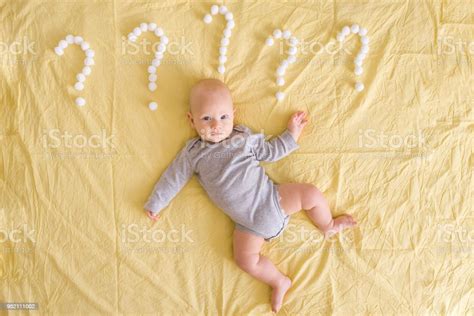 Top View Of Adorable Infant Child Lying Surrounded With Question Marks