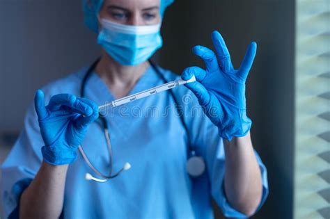 caucasian female doctor in hospital wearing face mask and surgical gloves holding swab test