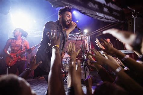 Male Singer Performing On Stage By Crowd At Nightclub Stock Image