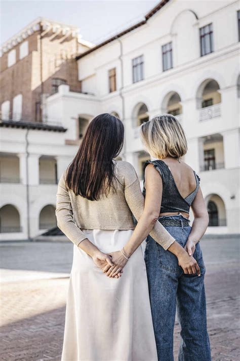 Female Friends Holding Hands Behind Backs Stock Photo