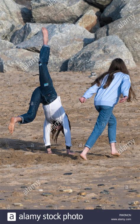 Young Teenage Girls Doing Handstands On Fistral Beach In Newquay