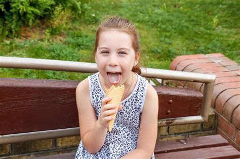 Premium Photo Funny Girl Licks Ice Cream While Sitting On A Park Bench