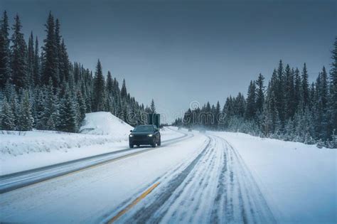 Car Driving On The Road Through Snowy Pine Forest And Blizzard In