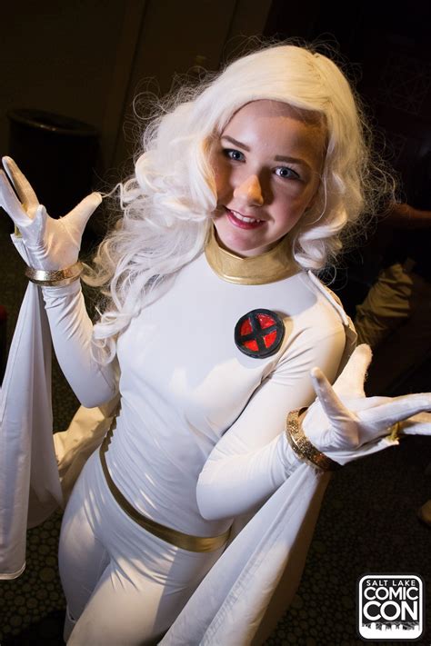 A Woman Dressed In White Is Posing With Her Hands Up And Wearing A Costume That Has A Red Cross