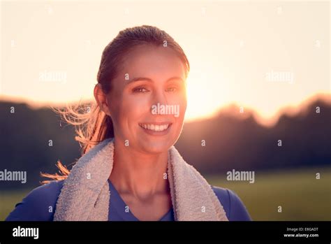 Attractive Woman Outdoors At Sunset Backlit By The Orange Glow Of The Sun Causing A Flare Around