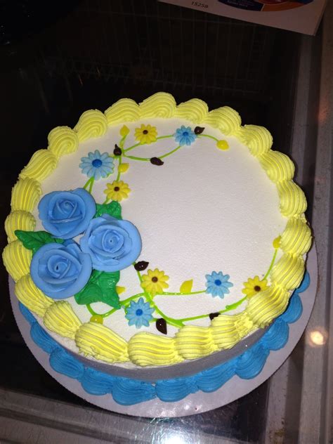 a cake with yellow frosting and blue flowers on it sitting on a glass table