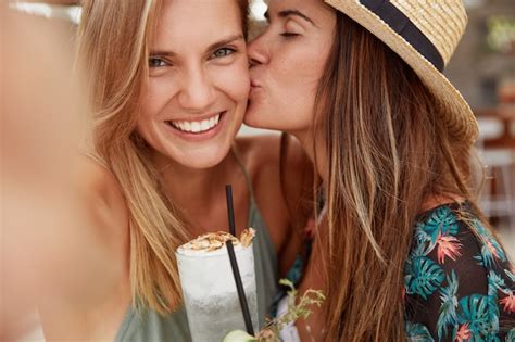 las mujeres lesbianas felices se hacen selfies se besan apasionadamente toman cócteles frescos