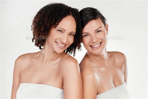 Cropped Portrait Of Two Beautiful Mature Women Posing Against A Grey
