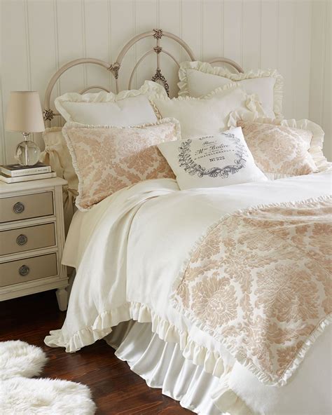 A White Bed Topped With Lots Of Pillows Next To A Night Stand And