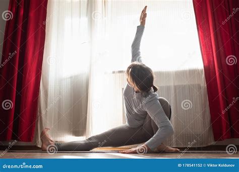 Caucasian Woman Doing Stretching Exercise In Living Room Stock Photo